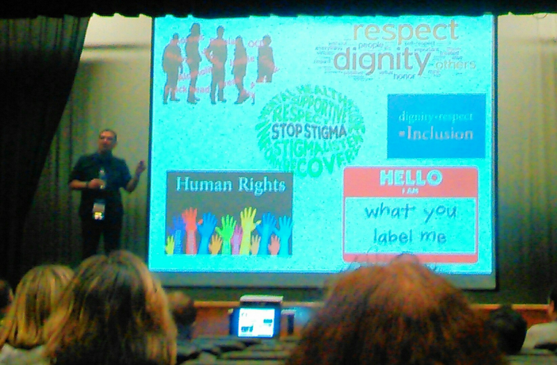 Presentor on Stage Referencing a Slideshow